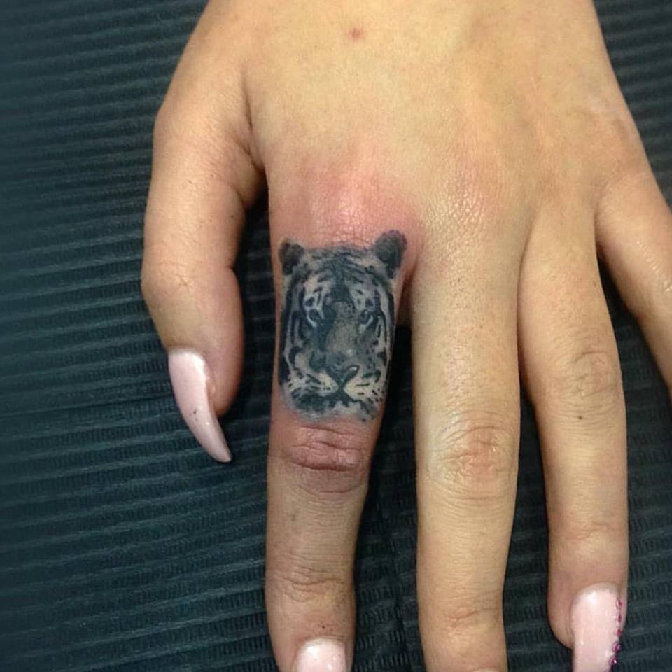 Tatuaje de microrealismo en blanco y negro de una cara de tigre en el dedo, realizado por Joni en Trip n' Tattoo Barcelona