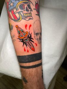 Tatuaje tradicional de una daga con un ojo central en colores vivos, realizado en el estilo Old School en Barcelona.