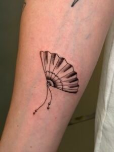 Tatuaje de un abanico en línea fina y puntillismo en el antebrazo, hecho por Joni Peralta